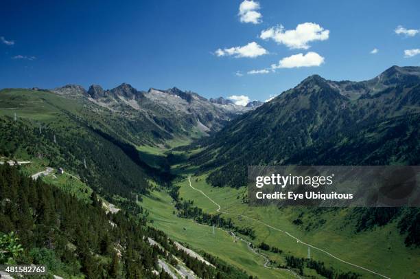 Spain, Pyrenees, Catalonia, Aran Valley. River valley landscape with road following the course of the river and electricity pylons.