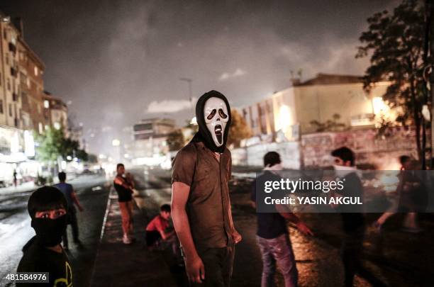 Masked protesters stand on the street in the Gazi district of Istanbul on July 22, 2015 two days after a suicide bomb attack killed at least 31...