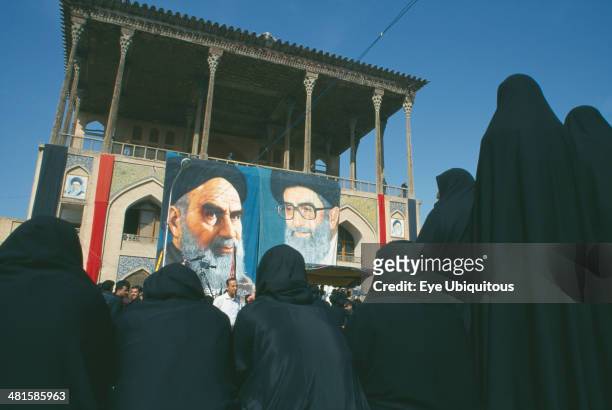 Iran, Esfahan, Banners of Ayatollah Khomeini and Ali Khamenei to commemorate death of Emam Husain with outlines of women in black in the foreground...