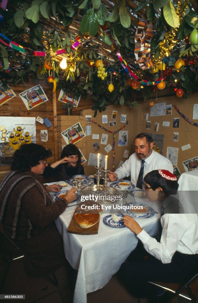 Jewish family eating a meal in a Sukka during the Sukkot Festival