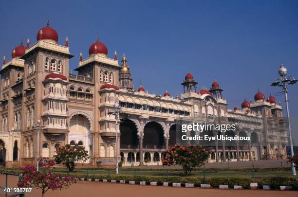 India, Karnataka, Mysore, Mysore Palace also known as Amba Vilas Palace completed in 1912 in Indo-Saracencic style. Exterior with flowering bushes.