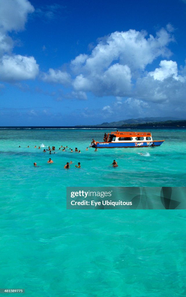 Tourists swimming beside a glass bottomed boat in the Nylon Pool in Buccoo Reef