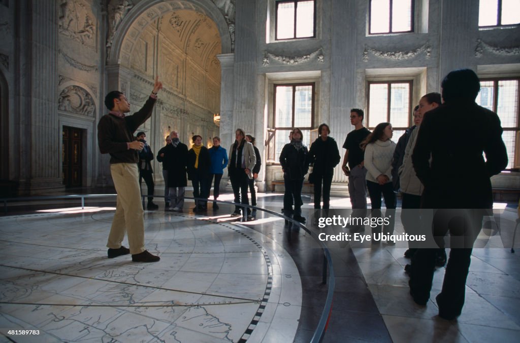 Visitors in the Citizens Hall of the Royal Palace, with tour guide standing on a map