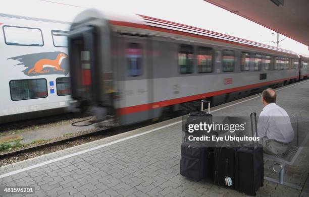 Austria, Vienna, Wien Westbahnhof. Passenger with luggage sitting on Vienna West Station with passing train. Also known as Vienna Western Station...