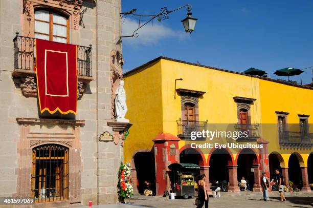 Mexico, Bajio, San Miguel de Allende, El Jardin Part view of Museo Casa de Allende and yellow painted arcades people and fruit juice vendor.