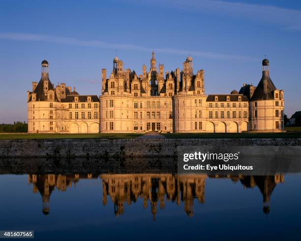Chateau Chambord in golden light, reflected in moat in foreground