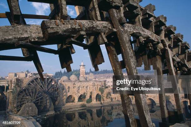 Syria, Wooden waterwheels on the Orontes river, framing the Al-Nuri Mosque