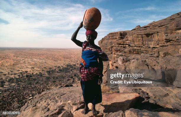 Mali, Bandiagara Escarpment, Water, Dogon woman returning to Tirelli village with empty pot carried on her head.