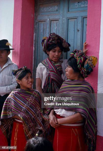 Guatemala, El Quiche, Nebaj, Ixil Indian women and girls gathered together at doorway in conversation. Wearing traditional dress with colorful shawls...