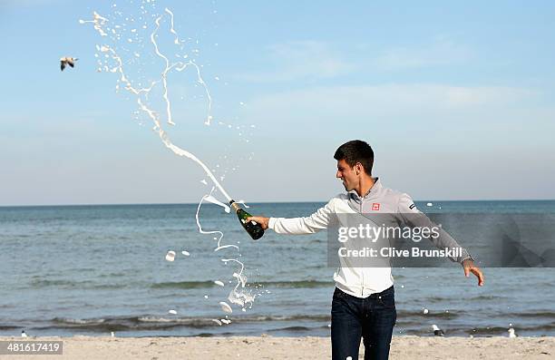 Novak Djokovic of Serbia celebrates by spraying champagne on Crandon Park beach after his straight sets victory against Rafael Nadal of Spain during...