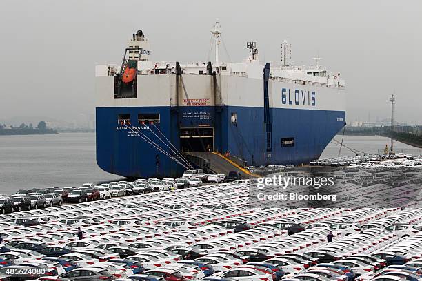 Hyundai Motor Co. Vehicles bound for export await shipment next to a Hyundai Glovis Co. Roll-on/roll-off cargo ship at a port near Hyundai Motor's...