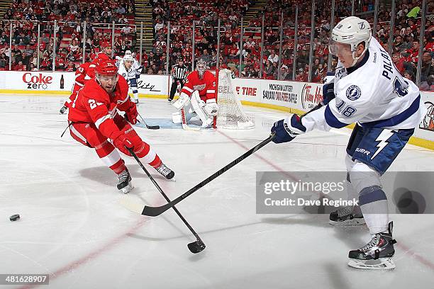 Ondrej Palat of the Tampa Bay Lightning passes the puck as Brian Lashoff of the Detroit Red Wings defends him during an NHL game on March 30, 2014 at...
