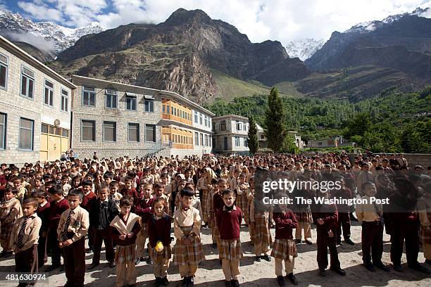 Students attending the morning assembly at Hasegawa Memorial Public School and College Karimabad, as The Ultar Peak seen in the rear on June 27, 2015...