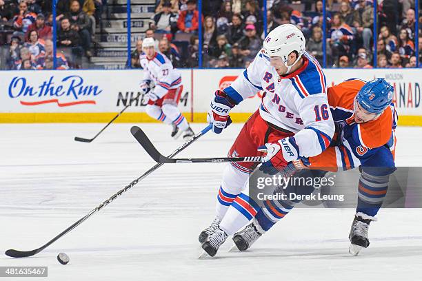 Mark Fraser of the Edmonton Oilers tries to check Derick Brassard of the New York Rangers during an NHL game at Rexall Place on March 30, 2014 in...