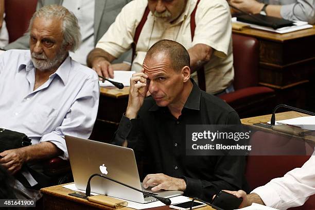 Yanis Varoufakis, Greece's former finance minister, center, looks on as he works on his Apple Inc. Laptop computer ahead of a vote on the terms of a...