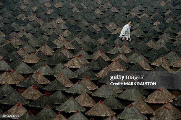 China-food-culture-lifestyle,FEATURE by Carol Huang This photo taken on February 22, 2014 shows a worker with some of the 5,000 pots of fermenting...
