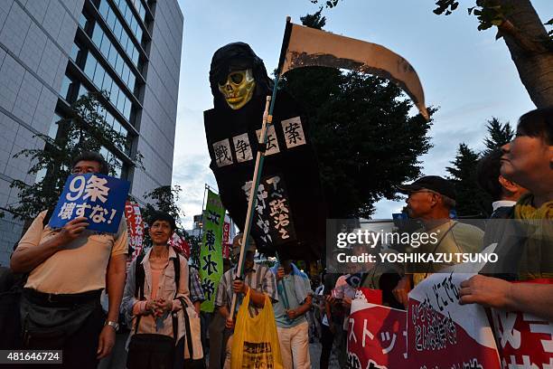 Civic group members hold placards and an effigy of the Grim Reaper during an anti-government rally outside the National Diet in Tokyo on July 23,...