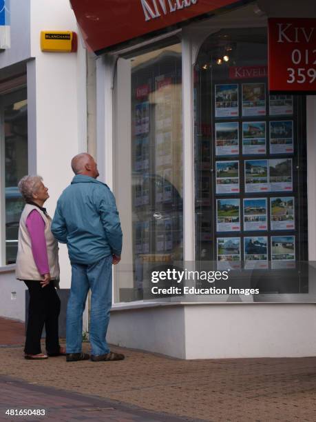 Old couple looking in estate agent's window, UK.