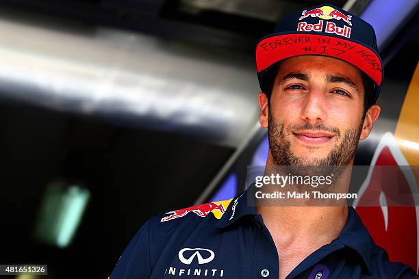 Daniel Ricciardo of Australia and Infiniti Red Bull Racing stands in the garage wearing a cap displaying a message in memory of Jules Bianchi during...