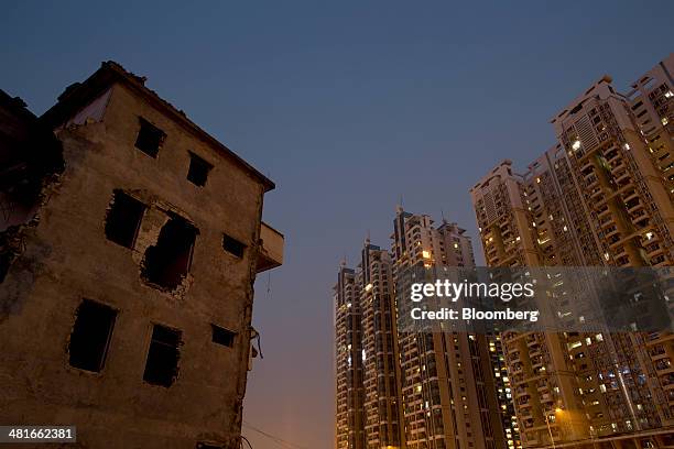 Partially demolished residential building, left, stands next to a Poly Real Estate Group Co. Residential complex in the Zhujiang New Town district of...