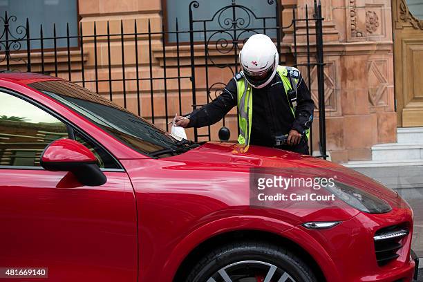 Traffic warden gives a parking ticket to a United Arab Emirates-registered Porsche Cayenne Turbo S on July 23, 2015 in London, England. London has...