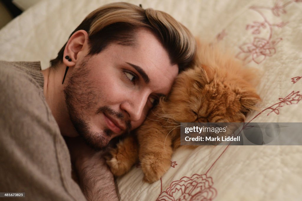 Handsome man resting his head on a sleeping cat