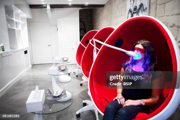 Reportage in a smile bar in Paris, France. Teeth whitening involves applying a whitening paste using a special mouthpiece, then exposing the teeth to...