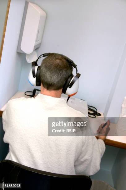 Patient taking an audiometry test. The test measures hearing levels.
