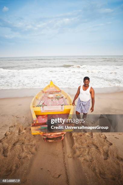 Fisherman with a fishing boat on the beach, Pondicherry, India.