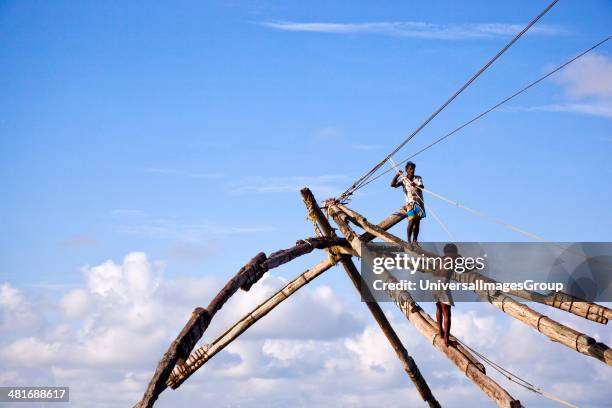 Two fishermen on Chinese fishing net, Cochin, Kerala, India.