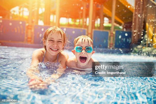 brother and sister having fun in water park - slide play equipment stock pictures, royalty-free photos & images