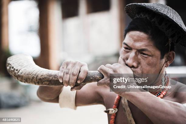 Naga tribesman blowing hunting horn during the annual Hornbill Festival at Kisama, Kohima, Nagaland, India.