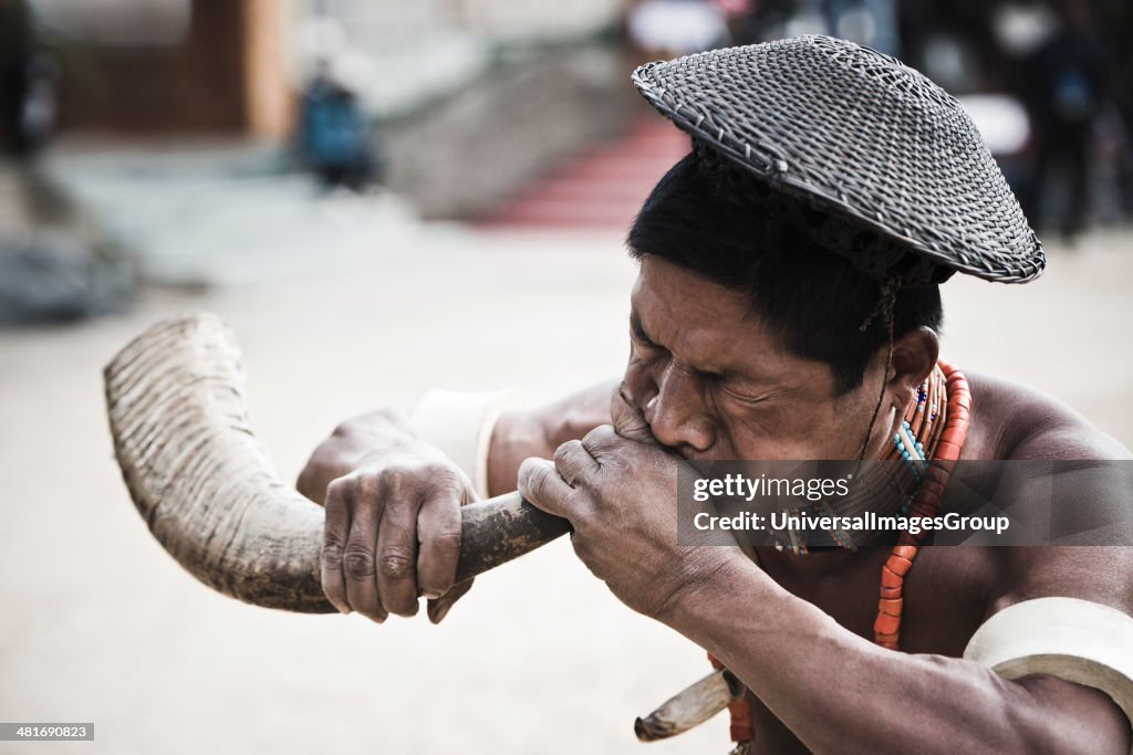 Naga tribesman blowing hunting horn during the annual Hornbill Festival at Kisama, Kohima, Nagaland, India