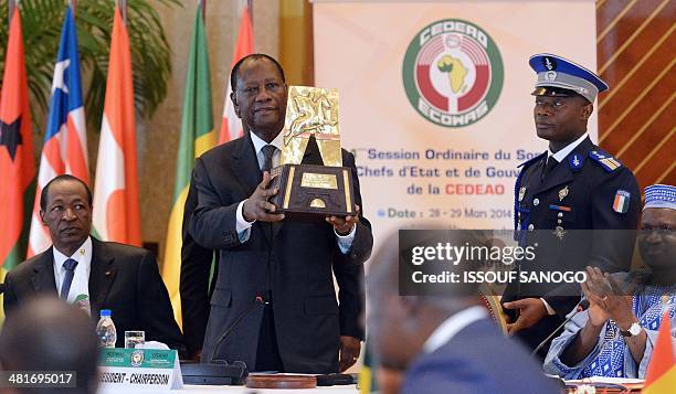 Ivory Coast President Alassane Dramane Ouattara speaks as he receives an award for his work on the crisis in Mali, alongside the Burkina Faso...