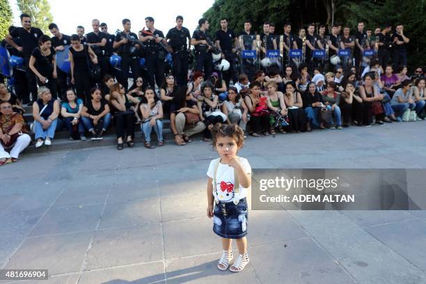 Young girl looks on as women sit in front of police officers during a protest denouncing a suicide bombing, that killed 32 activists on July 20 in...