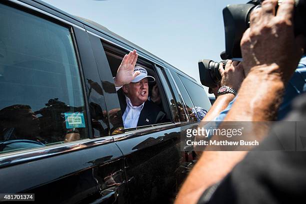 Republican Presidential candidate and business mogul Donald Trump talks to media from his car wearing a, "Make America Great Again," hat during his...