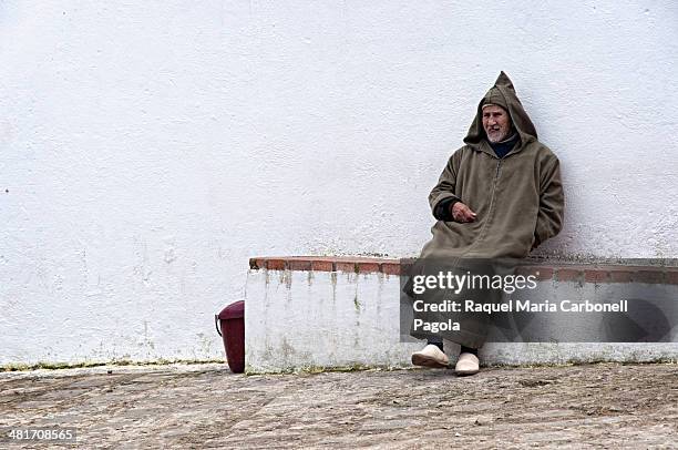 Elder man wearing traditional djellaba sitting on a bench.