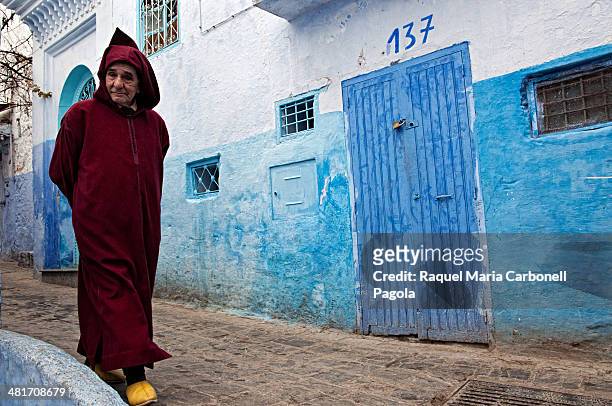 Man wearing traditional djellaba and walking by the blue streets.