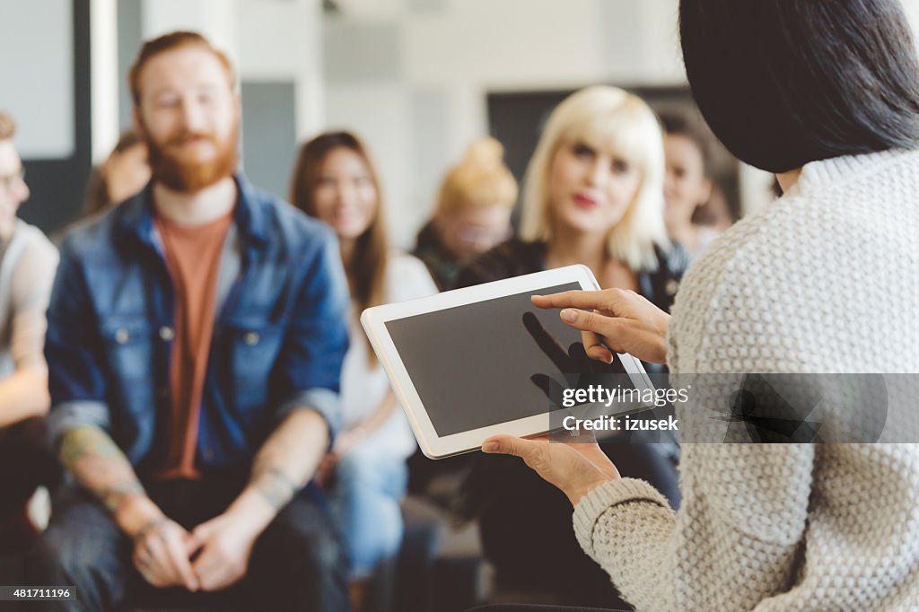 Teacher holding a digital tablet against auditorium
