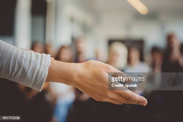 female hand against defocused group of students - female coach stock pictures, royalty-free photos & images