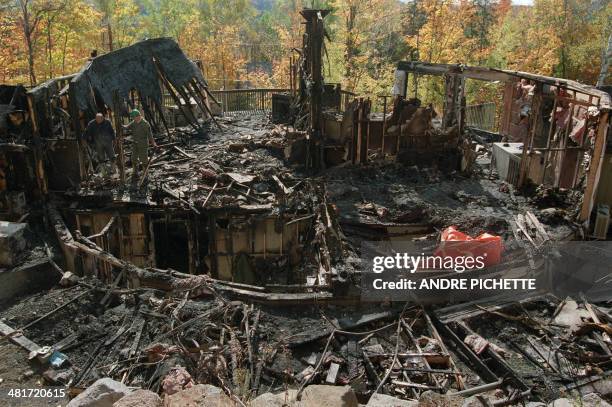 Two policemen from the Surete de Quebec search fro clues 05 October 1994 among the ruins of one of the chalets that was destroyed by fire in Morin...