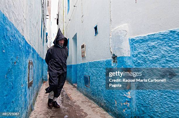 Man in traditional djellaba walking by the blue streets of the medina.