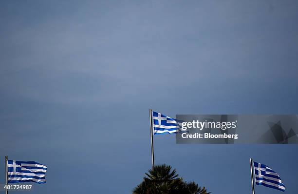 Three Greek national flags fly from flagpoles in Athens, Greece, on Monday, March 31, 2014. The European Commission predicts the Greek economy will...