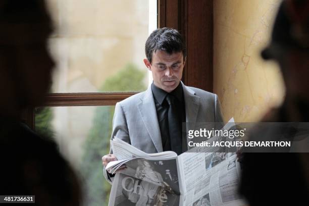 French MP and Evry mayor Manuel Valls reads Le Monde newspaper at the assembly in Paris before attending the weekly session of questions to the...
