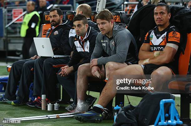 Chris Lawrence of the Wests Tigers watches on from the bench after leaving the field with an injury during the round 20 NRL match between the Wests...