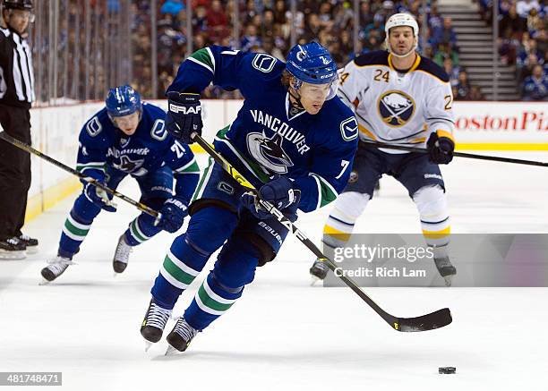 David Booth of the Vancouver Canucks drives to the net with the puck while teammate Zac Dalpe and Zenon Konopka of the Buffalo Sabres look on during...