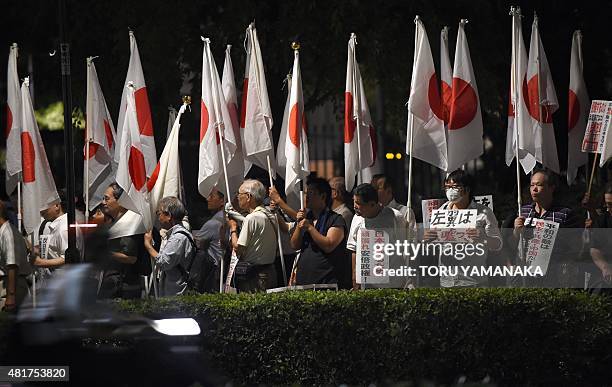 People hold Japanese national flags during a pro-government rally in front of the National Diet in Tokyo on July 24, 2015 to support the...