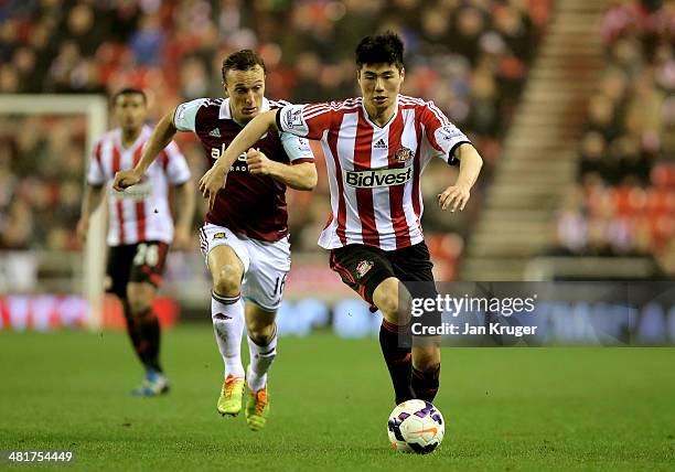 Ki Sung-Yong of Sunderland is pursued by Mark Noble of West Ham during the Barclays Premier League match between Sunderland and West Ham United at...