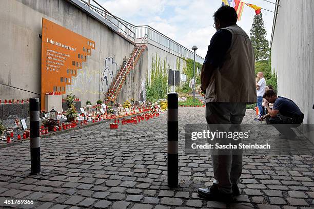 People look at candles and flowers left by mourners at the makeshift memorial to victims of the Love Parade disaster on its fifth anniversary on July...