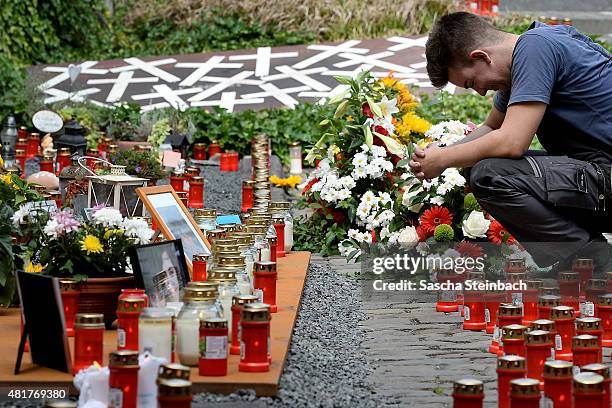 Man reacts looking at candles and flowers left by mourners at the makeshift memorial to victims of the Love Parade disaster on its fifth anniversary...